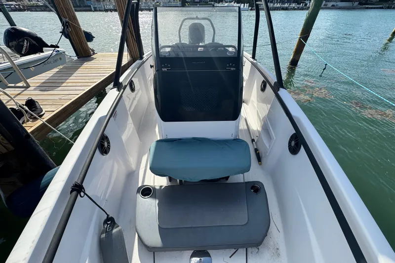Slide: The Image of 2022 Axopar 22 T-Top boat interior with seating and console, docked by the water. - 13