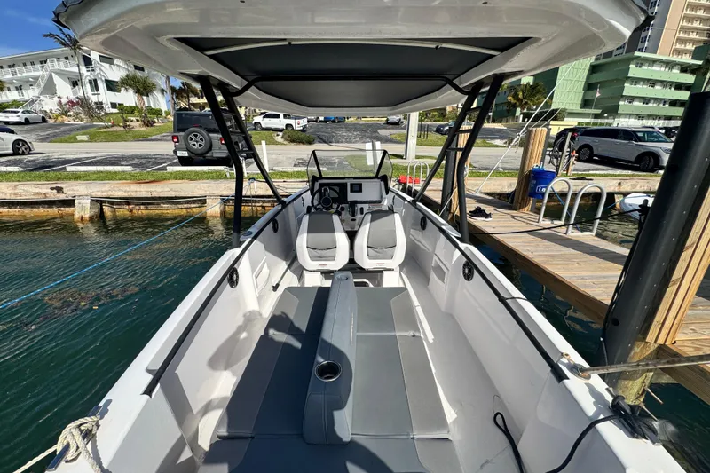 Slide: The Image of 2022 Axopar 22 T-Top boat docked, showcasing interior seating and helm. - 4