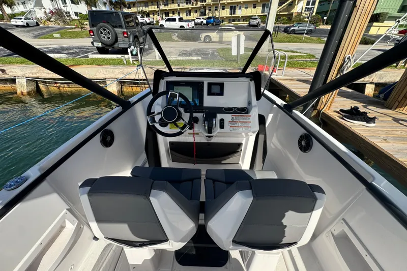 Slide: The Image of 2022 Axopar 22 T-Top boat cockpit with modern steering and controls, docked by the water. - 6