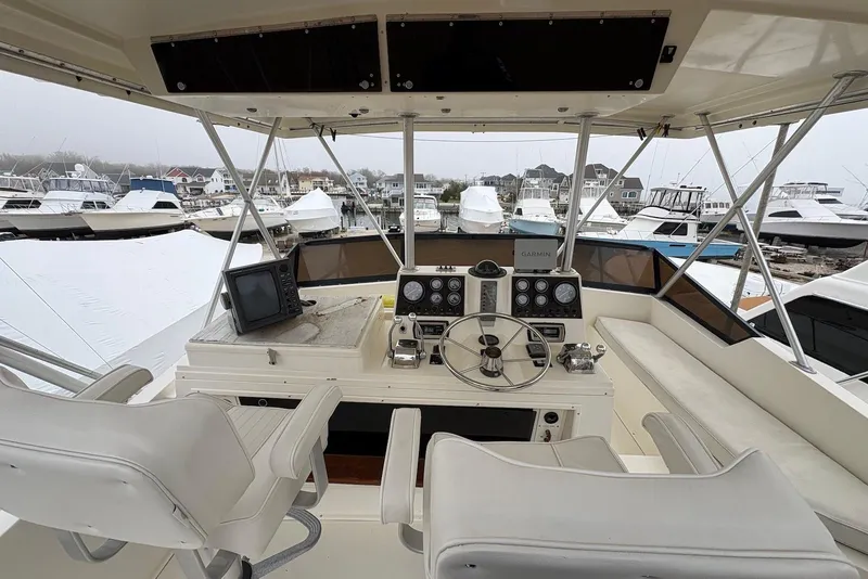 Slide: The Image of 1988 Viking 41 Convertible boat on land, with fishing rods and covered vessels nearby. - 7