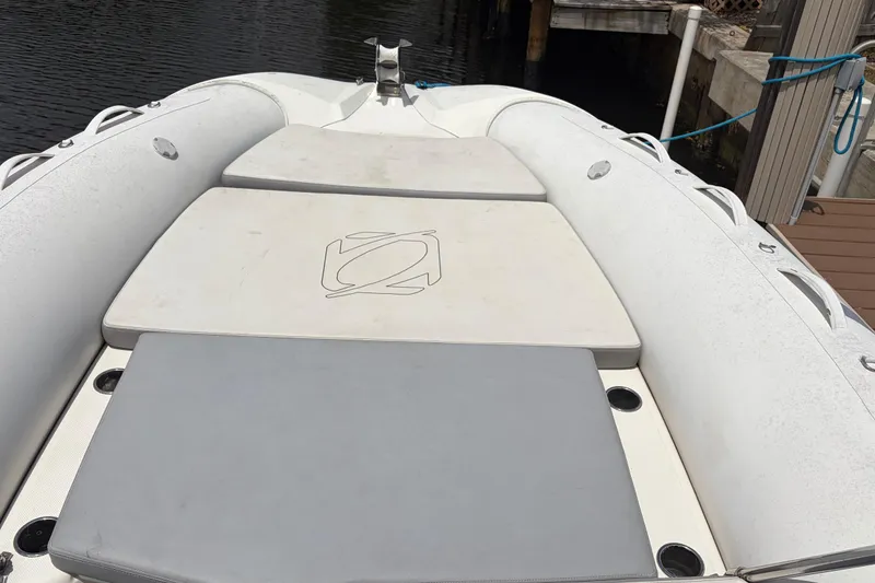 Slide: The Image of 2021 Zodiac N-ZO 680 boat with cushioned seating, docked by the water. - 15