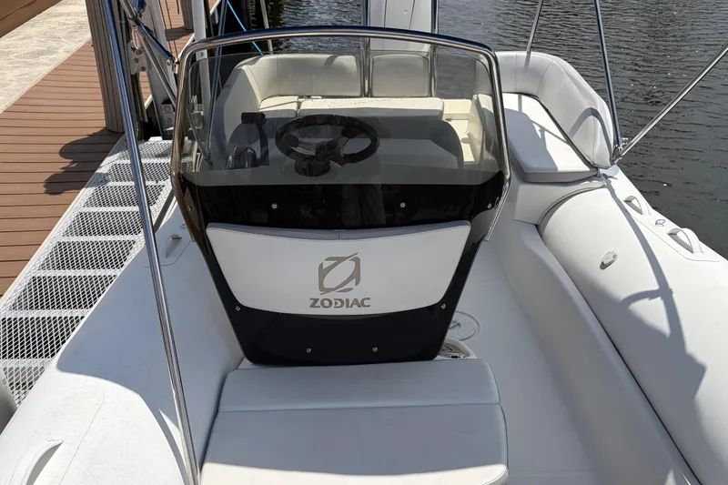 Slide: The Image of 2021 Zodiac N-ZO 680 boat interior with steering wheel and seating, docked by the water. - 16
