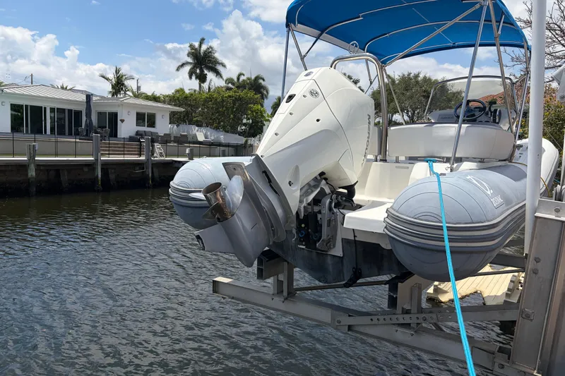 Slide: The Image of 2021 Zodiac N-ZO 680 boat with blue canopy docked by waterfront homes. - 2