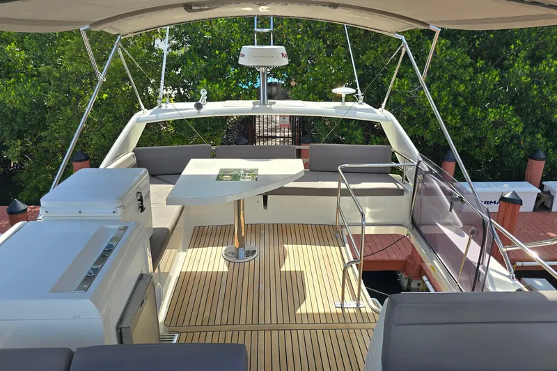 Slide: The Image of Flybridge of 2018 Prestige 460 yacht with seating and table, surrounded by lush greenery. - 12