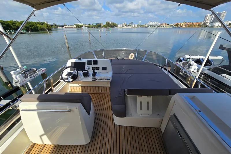 Slide: The Image of Flybridge of 2018 Prestige 460 yacht with helm station and seating, overlooking calm waters. - 13