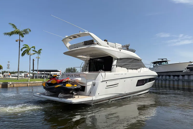 Slide: The Image of 2018 Prestige 460 yacht docked with jet skis, palm trees in background. - 1