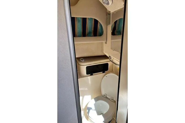 Slide: The Image of 1999 Grady-White Marlin 300 boat bathroom interior with striped curtains and compact design. - 22