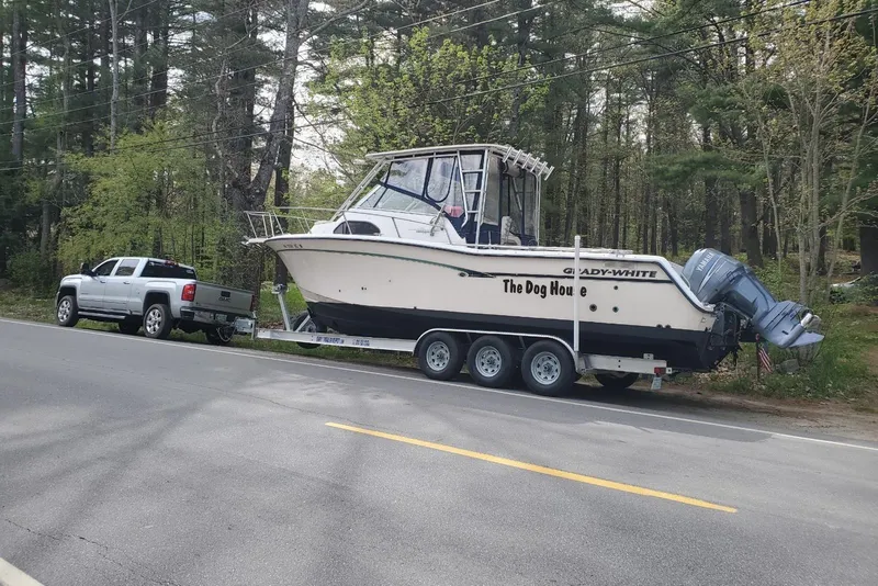 Slide: The Image of 1999 Grady-White Marlin 300 boat on trailer, parked roadside, forest background. - 28
