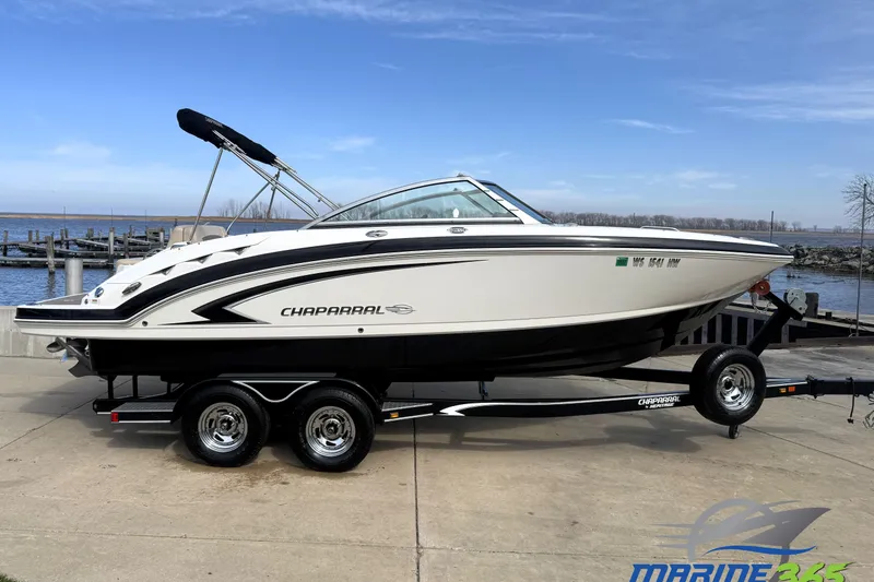 The Image of 2012 Chaparral 224 Sunesta boat on trailer by waterfront, clear sky background. - 0