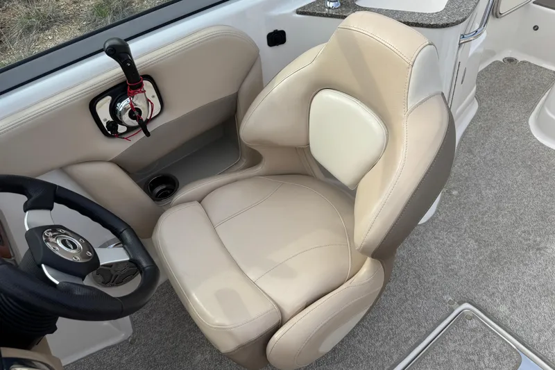 Slide: The Image of Captain's seat in 2012 Chaparral 224 Sunesta boat, featuring beige upholstery and steering wheel. - 13