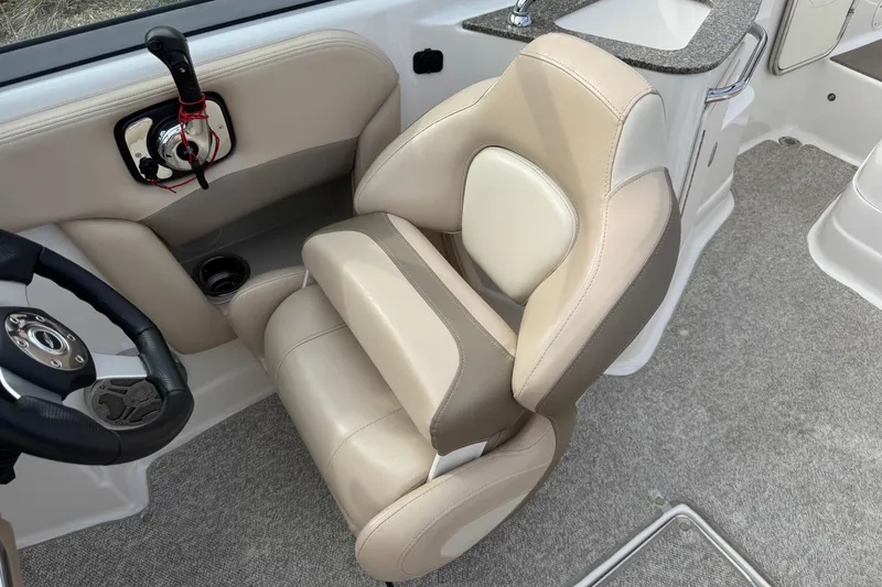 Slide: The Image of 2012 Chaparral 224 Sunesta boat interior with beige captain's chair and steering wheel. - 14