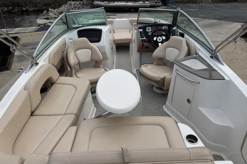 Slide: The Image of 2012 Chaparral 224 Sunesta boat interior with beige seating and a central table. - 19