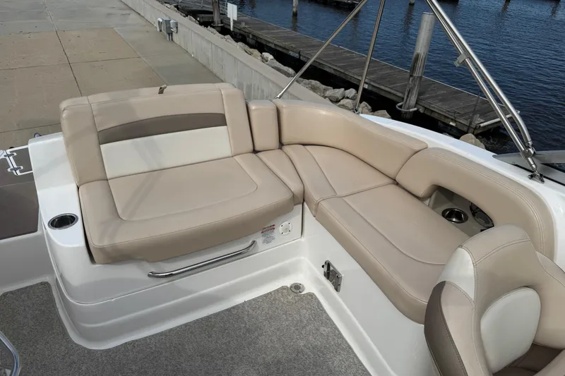 Slide: The Image of 2012 Chaparral 224 Sunesta boat interior with beige seating near a dock. - 28