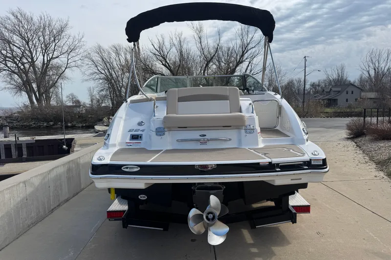 Slide: The Image of 2012 Chaparral 224 Sunesta boat docked, rear view with trees and cloudy sky. - 5