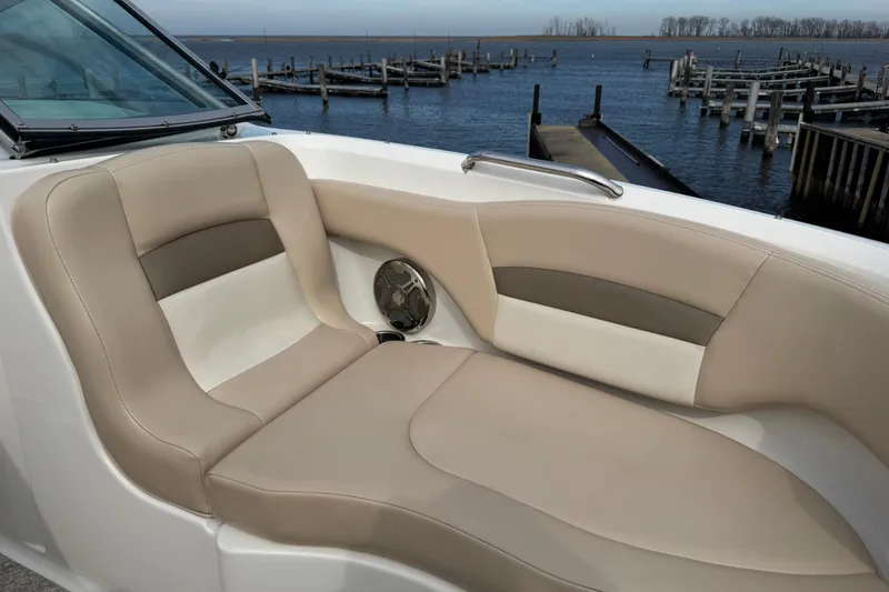 Slide: The Image of 2012 Chaparral 224 Sunesta boat interior with beige seating by a dock. - 8