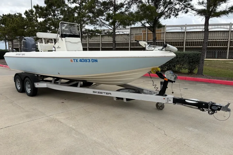 Slide: The Image of 2015 Skeeter SX2250 boat on trailer, parked outdoors near trees. - 2