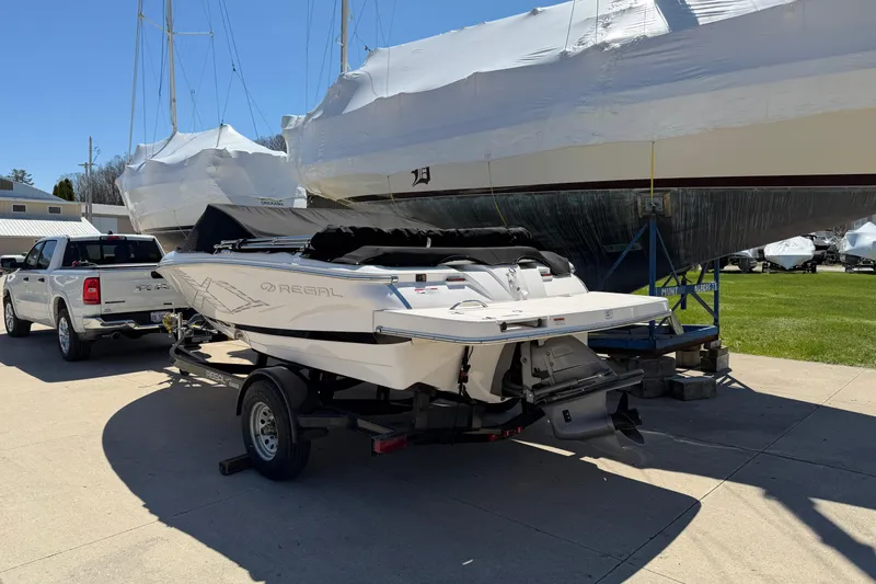 Slide: The Image of 2013 Regal 1900 Bowrider on trailer, parked beside a pickup truck and covered boats. - 2