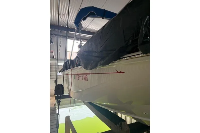 Slide: The Image of 2022 Boston Whaler 170 Montauk boat in storage, partially covered, with visible registration number. - 12