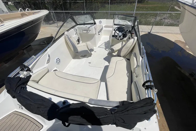 Slide: The Image of 2023 Stingray 191 DC boat interior with seating and steering wheel, parked outdoors. - 5
