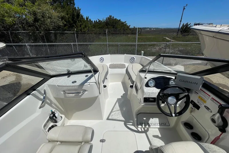 Slide: The Image of 2023 Stingray 191 DC boat interior with steering wheel, seating, and Garmin navigation system. - 7