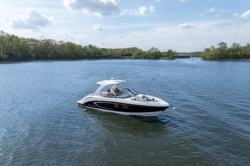 Slide: The Image of 2014 Chaparral 327 SSX boat cruising on a serene lake under a clear blue sky. - 0