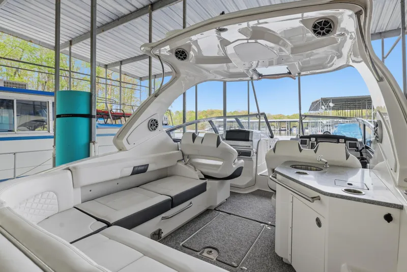Slide: The Image of 2014 Chaparral 327 SSX boat interior with seating and helm in a marina setting. - 15
