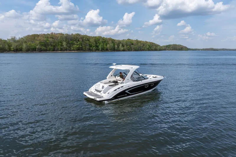 Slide: The Image of 2014 Chaparral 327 SSX boat cruising on a serene lake under a partly cloudy sky. - 2