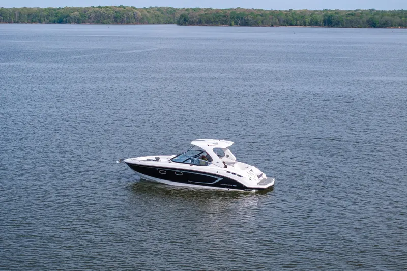 Slide: The Image of 2014 Chaparral 327 SSX boat cruising on a calm lake with forested shoreline. - 7