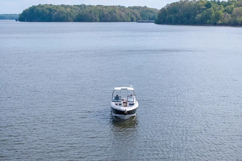 Slide: The Image of 2014 Chaparral 327 SSX boat on a serene lake with lush green shoreline. - 9