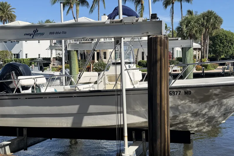 Slide: The Image of 2007 Boston Whaler 190 Montauk boat on lift, surrounded by palm trees and waterfront homes. - 25