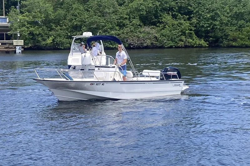 Slide: The Image of 2007 Boston Whaler 190 Montauk boat cruising on a calm river with lush greenery. - 3