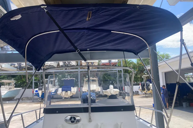 Slide: The Image of 2007 Boston Whaler 190 Montauk boat with blue canopy in a marina setting. - 9