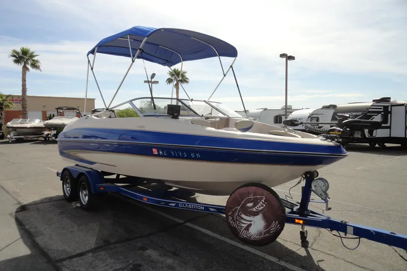 Slide: The Image of 2004 Glastron GX 205 Ski & Fish boat with blue canopy on trailer in parking lot. - 4