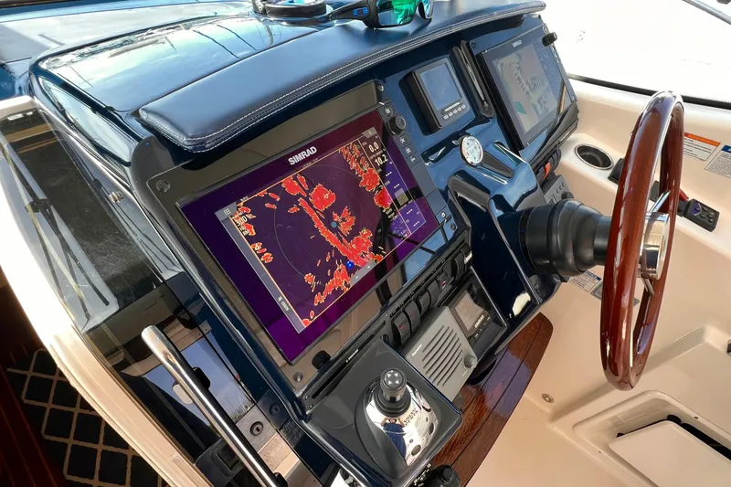 Slide: The Image of Control panel of a 2008 Tiara Yachts 3500 Sovran with navigation screens and wooden steering wheel. - 23
