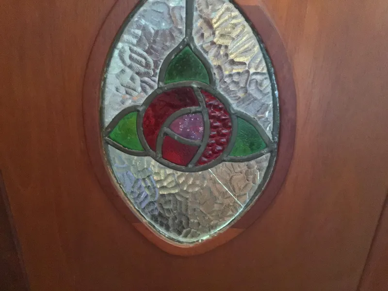 Slide: The Image of Stained glass window with red and green floral design on wood. - 21