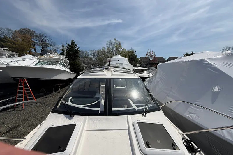 Slide: The Image of 2024 Solara S-250 Coupe boat docked, surrounded by other covered boats under a clear sky. - 22