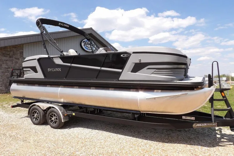 The Image of 2026 Sylvan R-22 LZ DH pontoon boat on trailer, parked outdoors. - 1