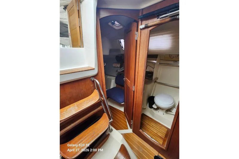 Slide: The Image of Interior of a 2002 Hunter 410 sailboat, featuring wooden finishes and compact bathroom. - 25
