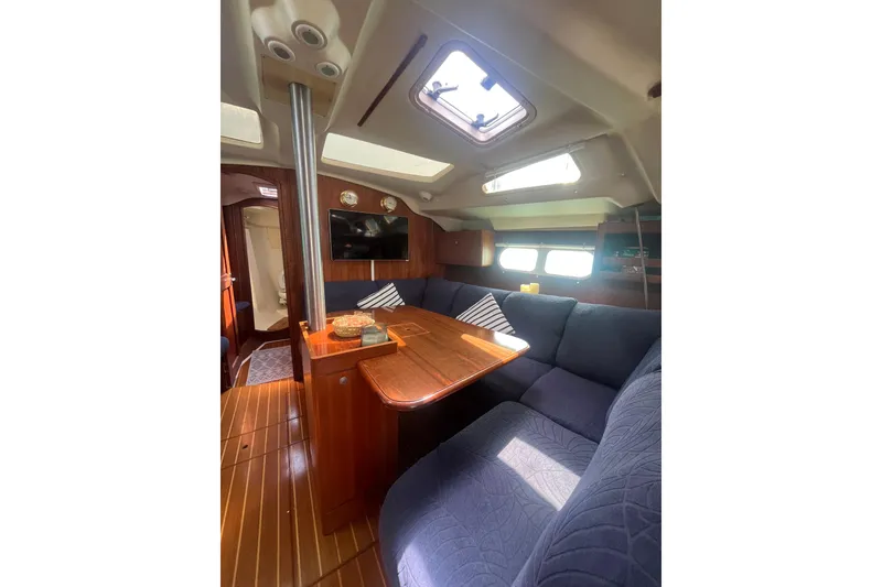 Slide: The Image of Interior of a 2002 Hunter 410 sailboat with cozy seating and wooden finishes. - 5