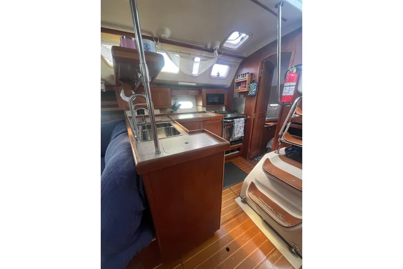 Slide: The Image of Interior of a 2002 Hunter 410 sailboat featuring a compact kitchen and wooden cabinetry. - 9