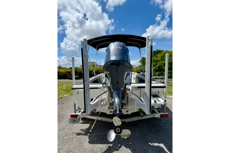 Slide: The Image of 2023 Key West 188 Bay Reef boat with outboard motor, parked on a trailer under a blue sky. - 30