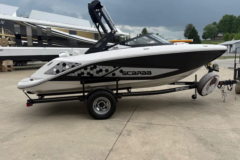 Slide: The Image of 2017 Scarab 195 H.O. boat on trailer, parked outdoors under cloudy sky. - 5