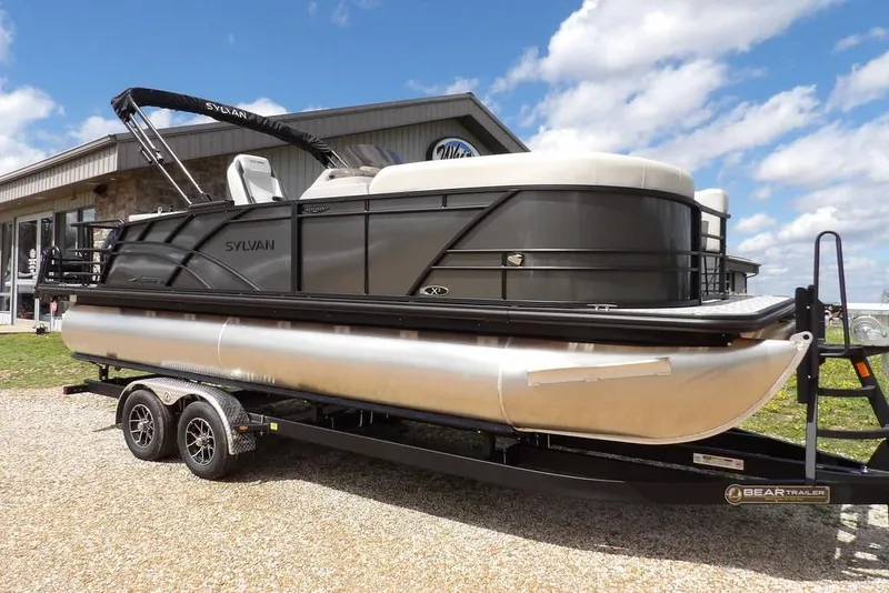 The Image of 2026 Sylvan X3 CLZ DH pontoon boat on trailer, parked outdoors under a blue sky. - 1
