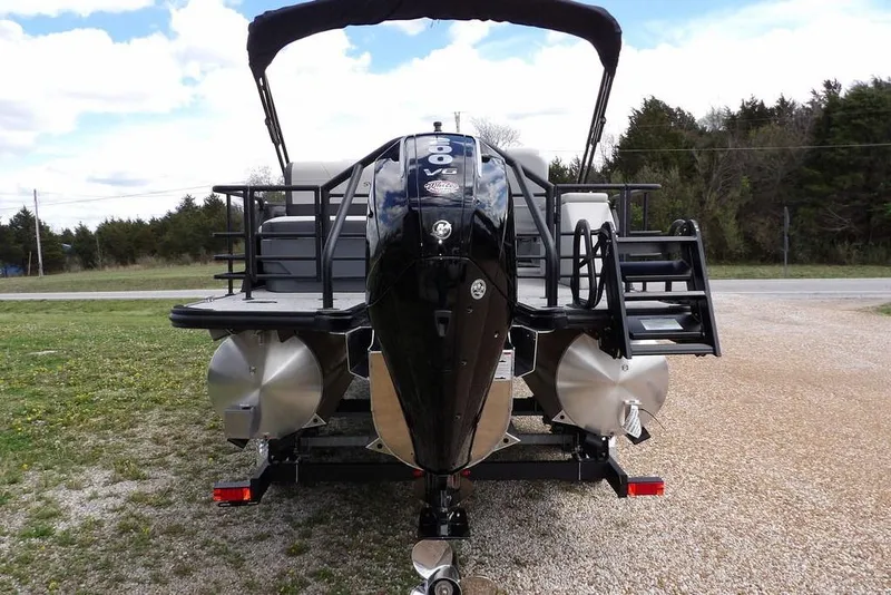 Slide: The Image of 2026 Sylvan X3 CLZ DH pontoon boat with powerful outboard motor, parked on gravel. - 6