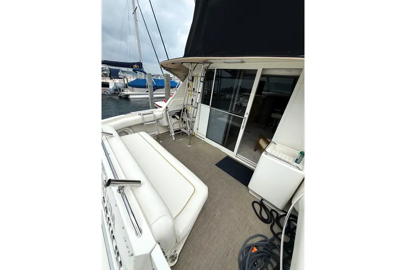 Slide: The Image of 1995 Sea Ray 370 Sedan Bridge yacht deck with seating and marina view. - 6