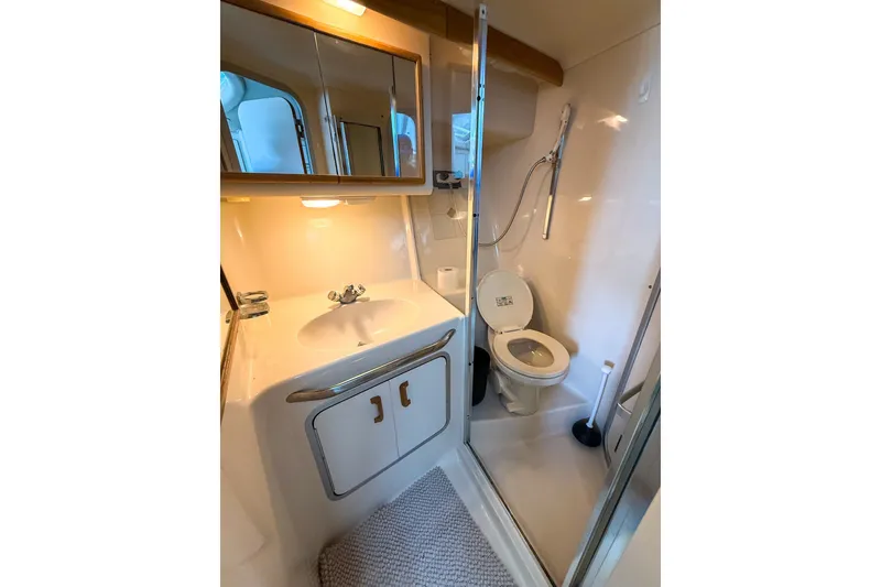 Slide: The Image of Bathroom interior of 1995 Sea Ray 370 Sedan Bridge yacht, featuring sink, toilet, and shower. - 22