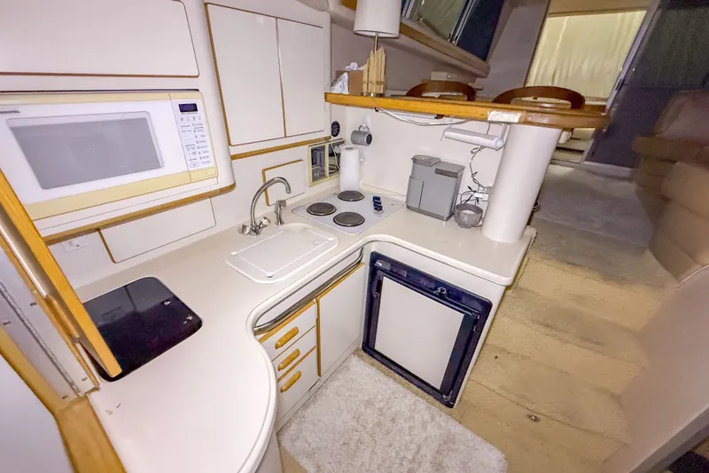 Slide: The Image of 1995 Sea Ray 370 Sedan Bridge yacht kitchen with microwave, sink, stove, and mini-fridge. - 16