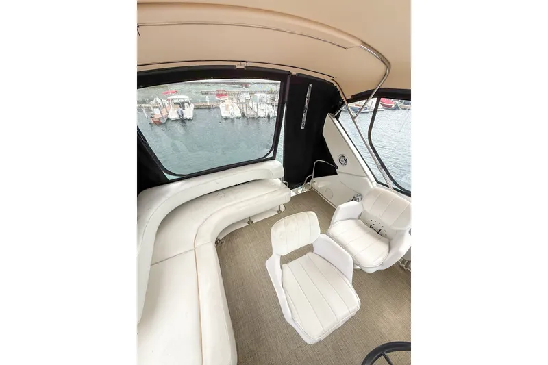 Slide: The Image of 1995 Sea Ray 370 Sedan Bridge interior with white seating and marina view. - 34