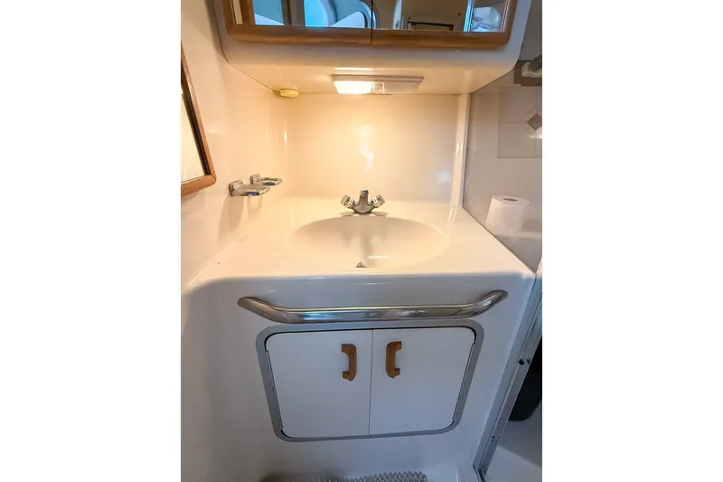 Slide: The Image of 1995 Sea Ray 370 Sedan Bridge bathroom sink with storage cabinet and mirror. - 23