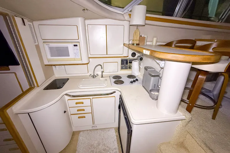 Slide: The Image of 1995 Sea Ray 370 Sedan Bridge kitchen with microwave, sink, stove, and compact design. - 15